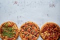 Three different kind of pizzas placed in a row on white rusty table Royalty Free Stock Photo