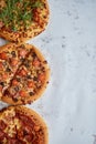 Three different kind of pizzas placed in a row on white rusty table Royalty Free Stock Photo