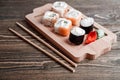 Three different kinds of Japanese rolls with wasabi and ginger on bamboo tray on beautiful wooden background Royalty Free Stock Photo