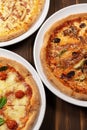 Three different pizzas on wooden background with tomato sauce, mixed cheese selection, ham and pork gyros Royalty Free Stock Photo