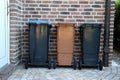 Three different plastic carbage cans are standing at the house wall in a row Royalty Free Stock Photo