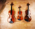 Three different size of violins put on wooden board Royalty Free Stock Photo