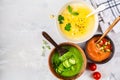 Three different vegetable cream soups in bowls on gray background. Corn, cucumber and gazpacho soups Royalty Free Stock Photo