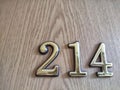 Three-dimensional brass numbers affixed to wood. Brass Numerals 214 Mounted on Wooden Surface