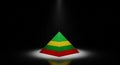 Geometric Pyramid with Red Green and Yellow Stripes Illuminated by Spotlight on Dark Background shape Royalty Free Stock Photo