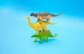 Three dinosaurs stand on each other on a blue background. Plastic toys Royalty Free Stock Photo