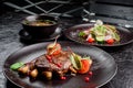 Grilled juicy steak with grilled mushrooms, tomatoes and cranberries on a dark round plate Royalty Free Stock Photo