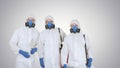 Three disinfectors walk in holding the disinfectant in their hands on gradient background.