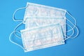 Three disposable protective medical masks with elastic with a nose clip on a blue