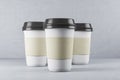 Three disposable white paper cup of coffee on table