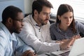 Three diverse colleagues looking at laptop screen working together indoors Royalty Free Stock Photo