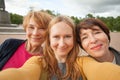 Three diverse happy women friends making selfie photo and having fun outdoors
