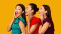 Three Diverse Models Sharing Secrets Standing Over Yellow Background, Panorama