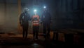 Three Diverse Multicultural Heavy Industry Engineers and Workers Walk in Dark Steel Factory Using