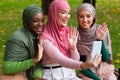 Muslim Ladies Making Video Call Using Phone Waving Hands Outdoors