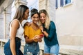 Three diverse young women having fun using mobile phone together outside Royalty Free Stock Photo