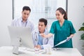 Three doctors discussing patient files on office