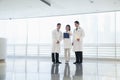 Three doctors standing and looking down at a document in the hospital, full length Royalty Free Stock Photo