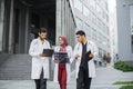 Three doctors, woman in hijab and two men in medical apparel, discussing patient's x-ray CT scan
