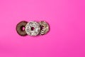 Three donuts with chocolate and icing on pink background. View from above Royalty Free Stock Photo