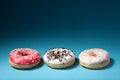 Three donuts with color icing on blue background