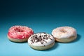 Three donuts with color icing isolated on blue background Royalty Free Stock Photo