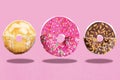 Three donuts, Cream, chocolate and pink glazed are cut and drawn fly in air Royalty Free Stock Photo