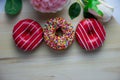 Three donuts of different colors lie on a wooden stand