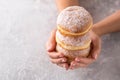 Three donuts in female hands on a gray background