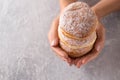 Three donuts in female hands on a gray, top view