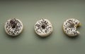 Three donuts with white glaze and chocolate sprinkles on a grreen or gray background, one of them bitten Royalty Free Stock Photo