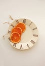 Three orange slices on small plate on light gray background.
