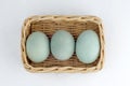 three duck eggs in a rattan basket on white background