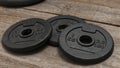 Three dumbbell discs for weight lifting on wooden floor Royalty Free Stock Photo