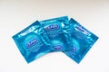 Three Durex condoms in blue packaging on a white background