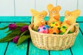 Three easter bunnies with colored easter eggs on a wooden tabel