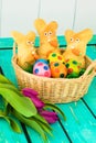 Three easter bunnies with colored easter eggs on a wooden tabel