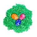 Three Easter eggs lying in a green paper nest from above