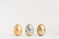 Three Easter golden decorated eggs on blue background. Minimal easter concept. Happy Easter card with copy space for