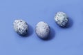 Three easter marbled purple eggs on blue background Royalty Free Stock Photo