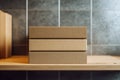 Three eco-friendly stacked rectangular cardboard boxes on a wooden shelf with a textured grey stone background wall in soft Royalty Free Stock Photo