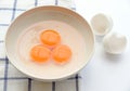 Three egg yorks and egg shell in bowl on tablecloth Royalty Free Stock Photo