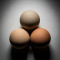 Three eggs are arranged in a triangular formation on a smooth, white Royalty Free Stock Photo