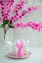 Three eggs bunny in a colored paper wrapper on a plate and table in a cherry blossoms. The Easter holiday Royalty Free Stock Photo