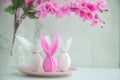 Three eggs bunny in a colored paper wrapper on a plate and table in a cherry blossoms. The Easter holiday Royalty Free Stock Photo