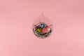 Three eggs in a floating glass nest. Pink background. Creative Easter concept