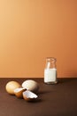 Three eggs with milk in glass bottle on brown background Royalty Free Stock Photo