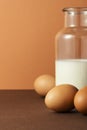 Three eggs with milk in glass bottle on brown background Royalty Free Stock Photo