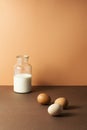 Three eggs with milk in glass bottle on brown background Royalty Free Stock Photo