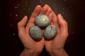 Three eggs, painted hibiscus tea on a black background, in men`s palms and crumbs of sugar glaze, like a dragon egg Royalty Free Stock Photo